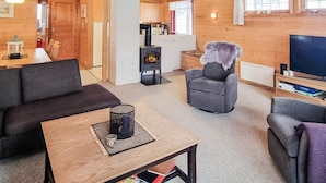 A cozy living room with a sofa, armchairs, a coffee table, and a fireplace. - 6 Person Holiday Home in Aseral (Aseral)