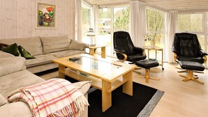 A modern living room with a sofa, two black leather chairs, a wooden coffee table, and a painting on the wall. - 4 Star Holiday Home in Albaek (Aalbaek)