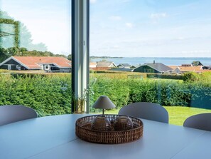 A dining area with a table, chairs, and a view of houses and water.
