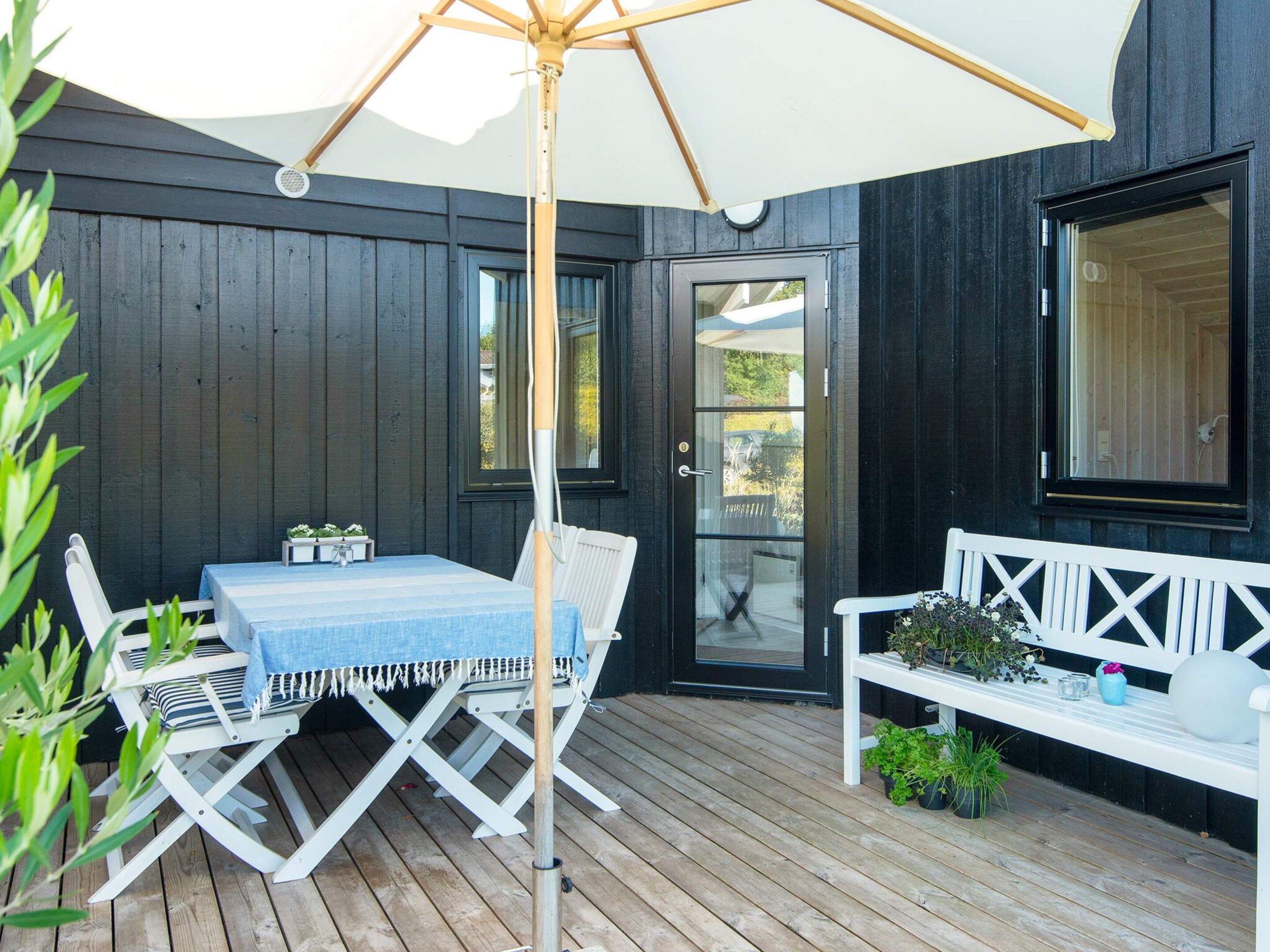 A wooden deck with a table and chairs, a bench, and a large umbrella.
