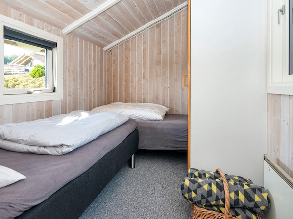 A small, compact room with two beds, a window, and a view of the outside.