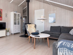 A modern living room with a sofa, a chair, a small table, and a cabinet. - 4 Star Holiday Home in Sjolund (Sjølund)