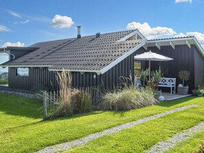 A modern house with a sloped roof, a covered patio, and a well-maintained lawn.