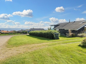 A residential area with a grassy lawn, a pathway, and a building with a sloped roof.