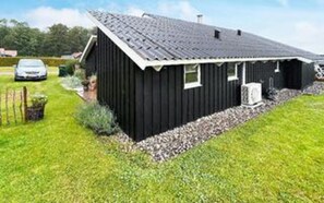 A black single-story building with a sloped roof, a small porch, and a gravel driveway. - 4 Star Holiday Home in Sjolund (Sjølund)