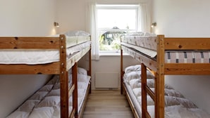 A room with two bunk beds, a window with curtains, and a radiator.