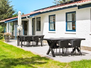 A building with a white exterior and blue trim, featuring a patio with a table and chairs.