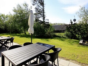 An outdoor patio with a table and chairs, surrounded by a grassy area and trees. - 4 Star Holiday Home in Fjerritslev (Fjerritslev)