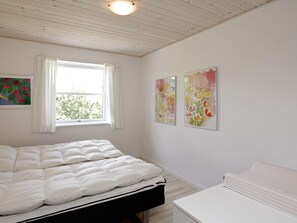 A bedroom with a bed, a window, and two wall-mounted paintings.