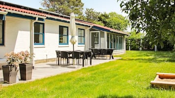 En bygning med en overdækket terrasse, udendørs siddepladser og en have.