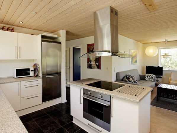 A modern kitchen with a built-in stove, oven, and stainless steel refrigerator.