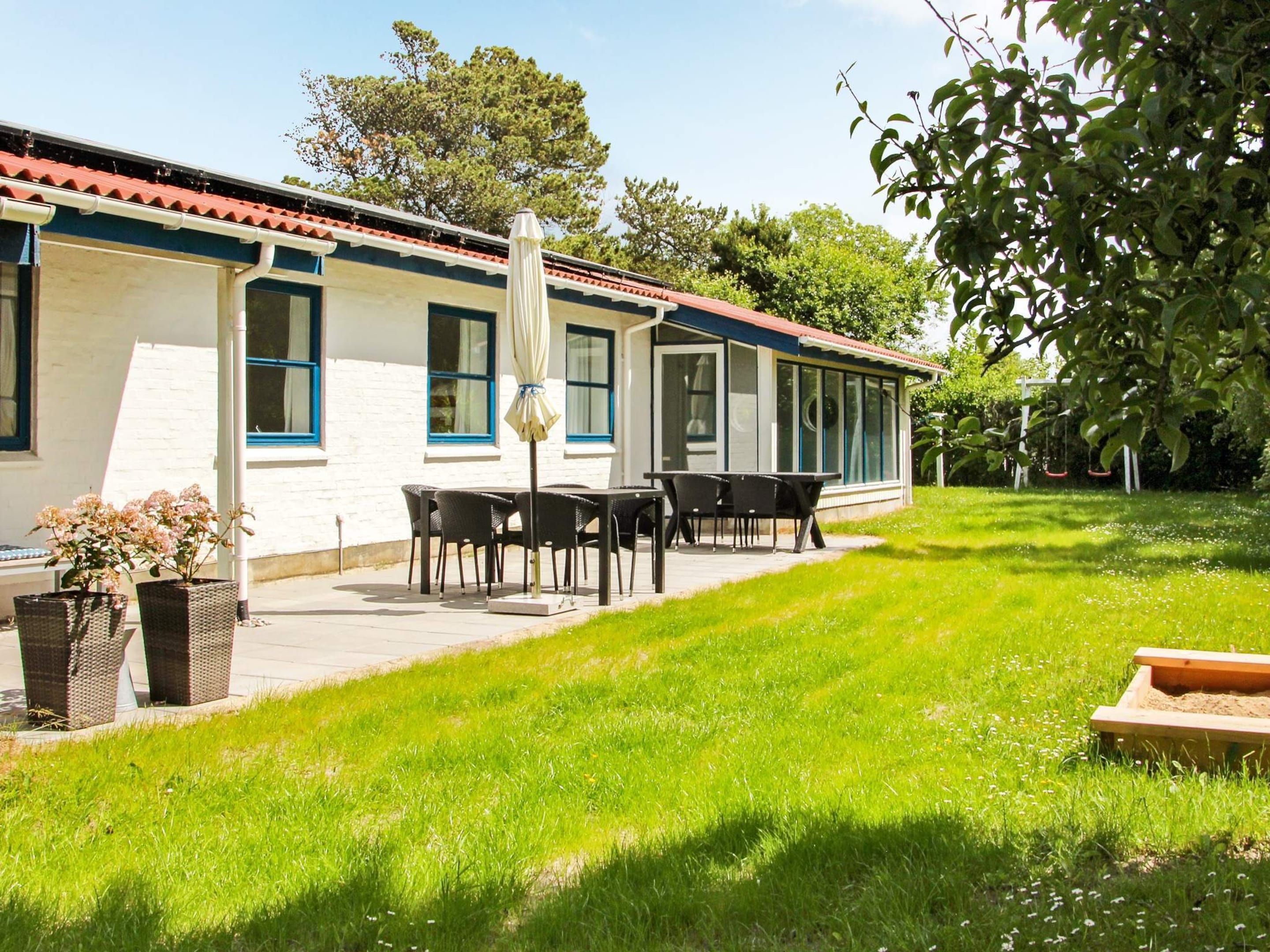 Et hus med en patio, et bord med stole og et gyngestativ.