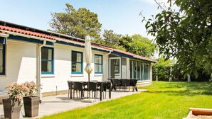 Una casa con patio, una mesa con sillas y un columpio.