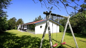 A house with a covered patio, a swing set, and a lawn. - 4 Star Holiday Home in Fjerritslev (Fjerritslev)
