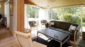 A room with a wooden ceiling, a sofa, a table, and a chair.