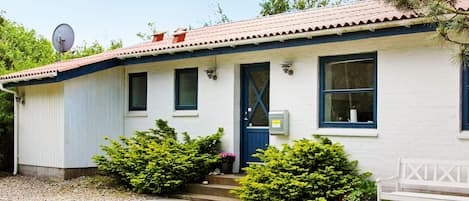 Un bâtiment d’un seul étage avec une porte bleue, une antenne parabolique et un petit espace porche.