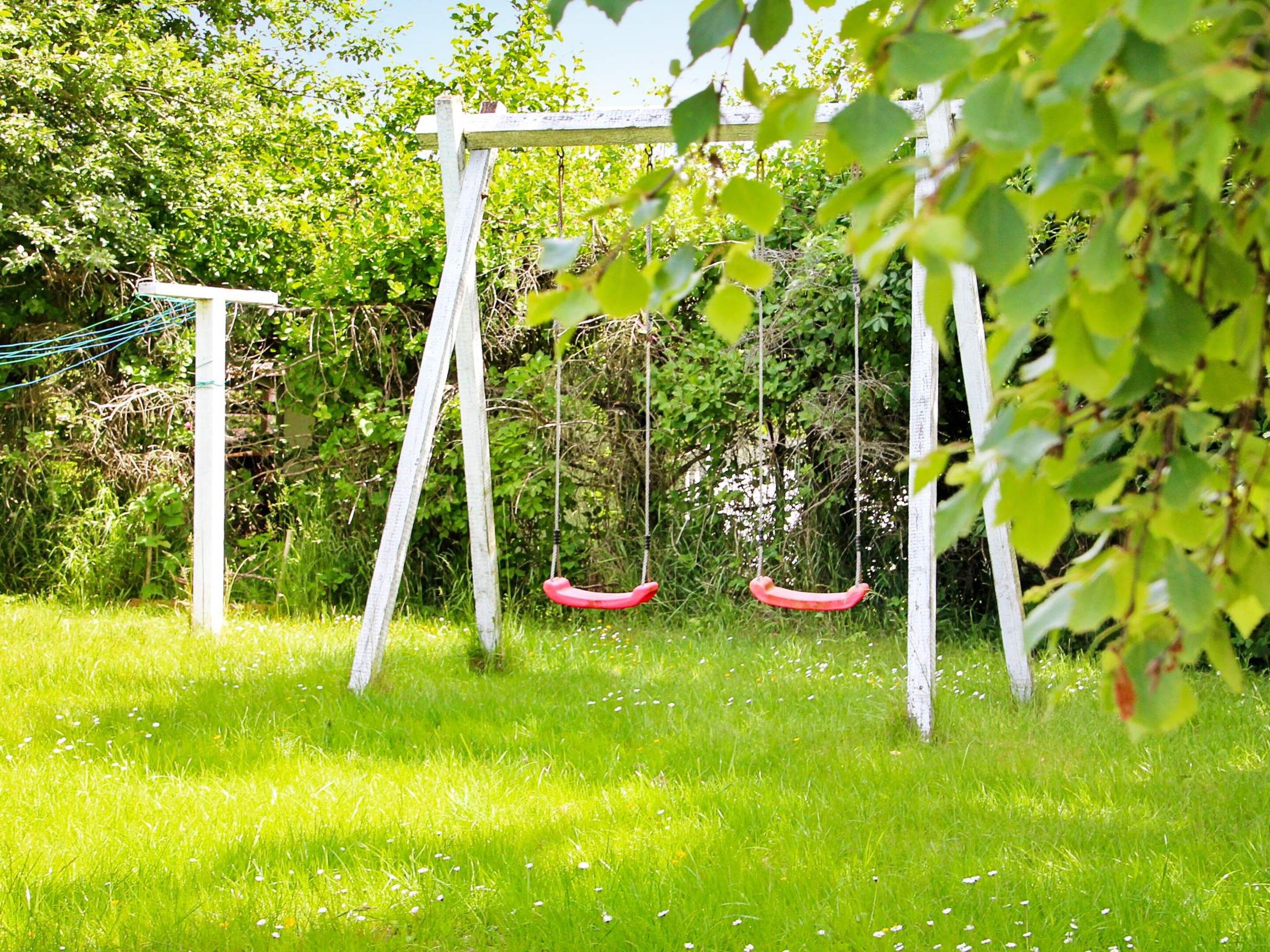 A swing set in a grassy area with trees in the background.