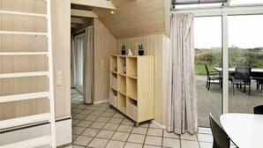 A modern interior with a wooden floor, a built-in bookshelf, a dining area with a table and chairs, and a view of the outdoors through large windows. - Sprawling Holiday Home With Swimming Pool in Ringkøbing (Ringkobing)