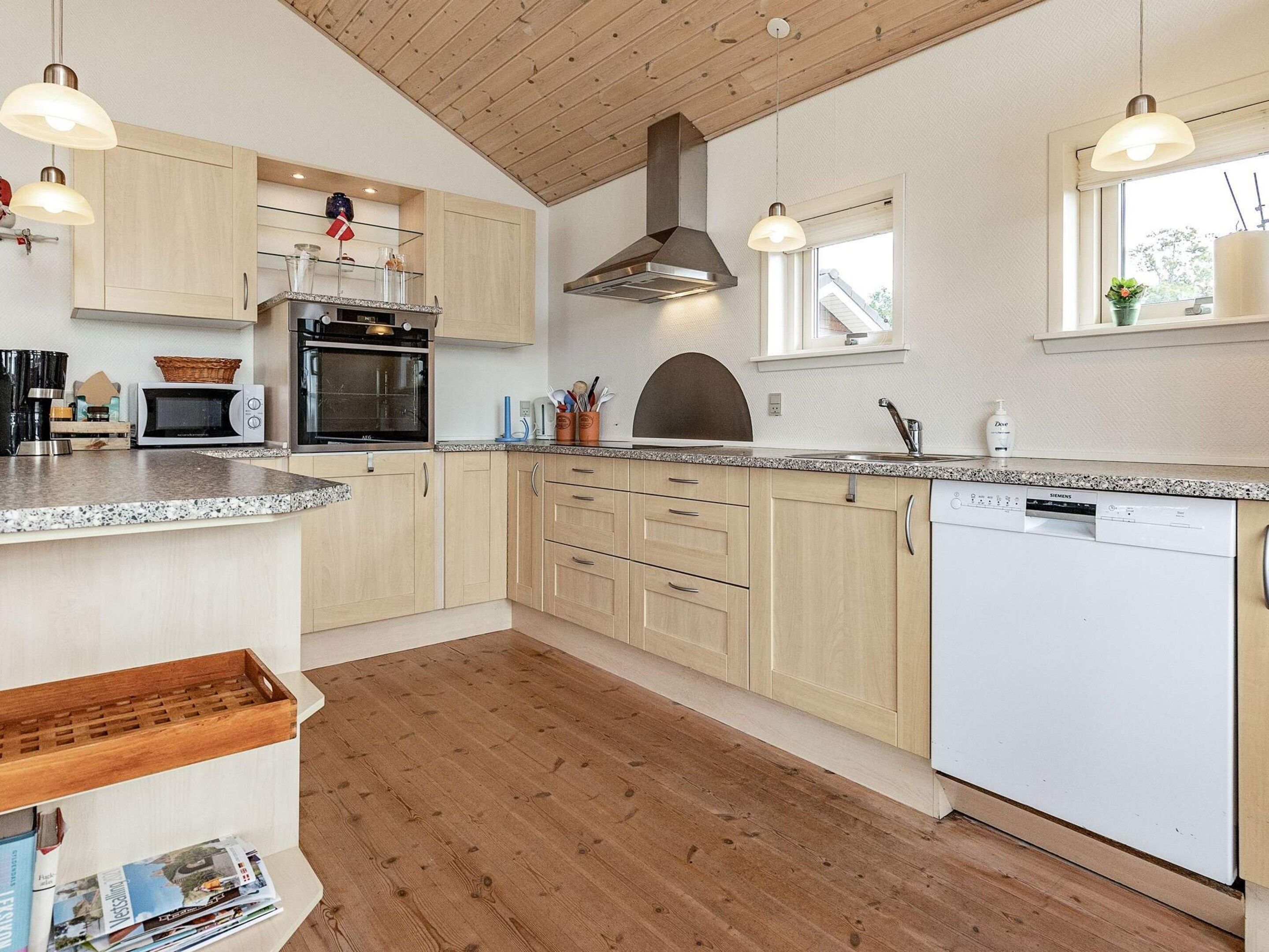 A modern kitchen with wooden cabinets, a built-in oven, a dishwasher, and pendant lighting.