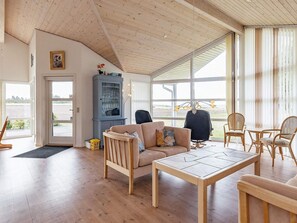 A spacious living room with a wooden ceiling, large windows, a sofa, chairs, and a table. - 5 Star Holiday Home in Spottrup (Spøttrup)