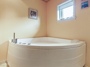 A corner bathroom with a freestanding bathtub, a window, and a framed picture on the wall. - 5 Star Holiday Home in Spottrup (Spøttrup)