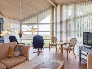 A modern living room with a sofa, chairs, a dining table, and a TV. - 5 Star Holiday Home in Spottrup (Spøttrup)