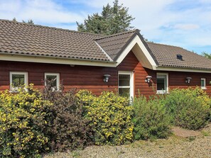 A red wooden house with a tiled roof, a front door, and two windows. - 5 Star Holiday Home in Spottrup (Spøttrup)