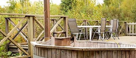 Eine Holzterrasse mit einer Sitzgruppe in Kreisform, Metallgeländer und Gartenmöbeln.