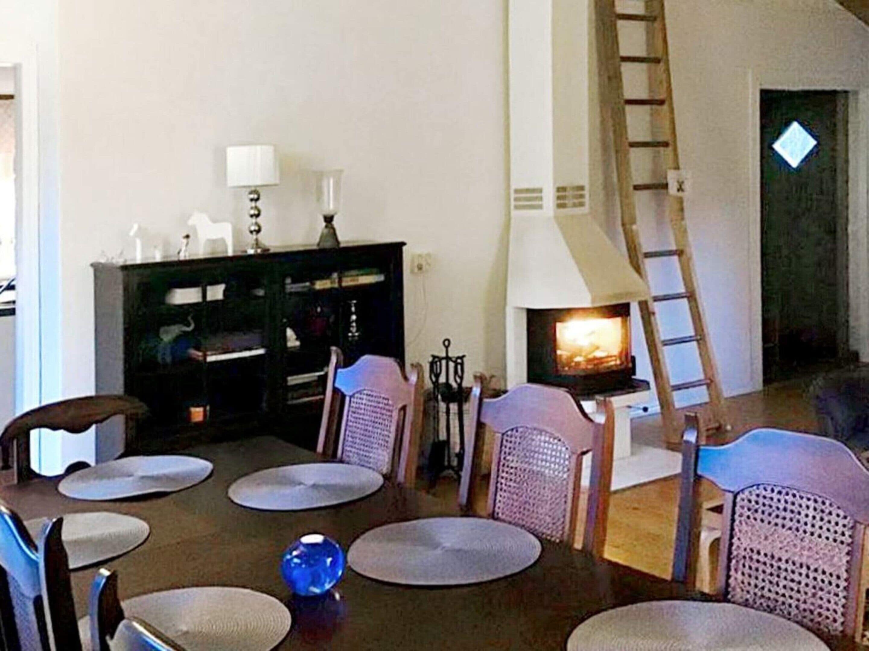 En stue med pejs, et spisebord med stole og en bogreol.