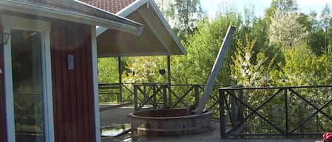 A wooden deck with a hot tub, a covered area, and a railing.