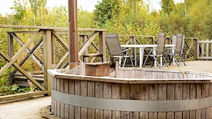 A wooden deck with a circular seating area, metal railing, and outdoor furniture. - Holiday Home in GrÃ¤smark (Gränna)