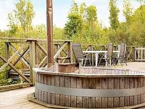 A wooden deck with a circular seating area, metal railing, and outdoor furniture. - Holiday Home in GrÃ¤smark (Gränna)