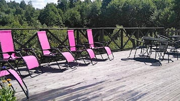 Ett trädäck med rosa stolar och bord, omgivet av ett metallräcke.