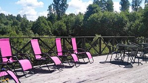 A wooden deck with pink chairs and tables, surrounded by a metal railing. - Holiday Home in GrÃ¤smark (Gränna)