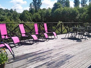 A wooden deck with pink chairs and tables, surrounded by a metal railing. - Holiday Home in GrÃ¤smark (Gränna)