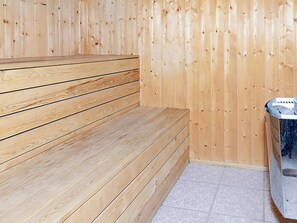 A wooden sauna with benches and a tiled floor.