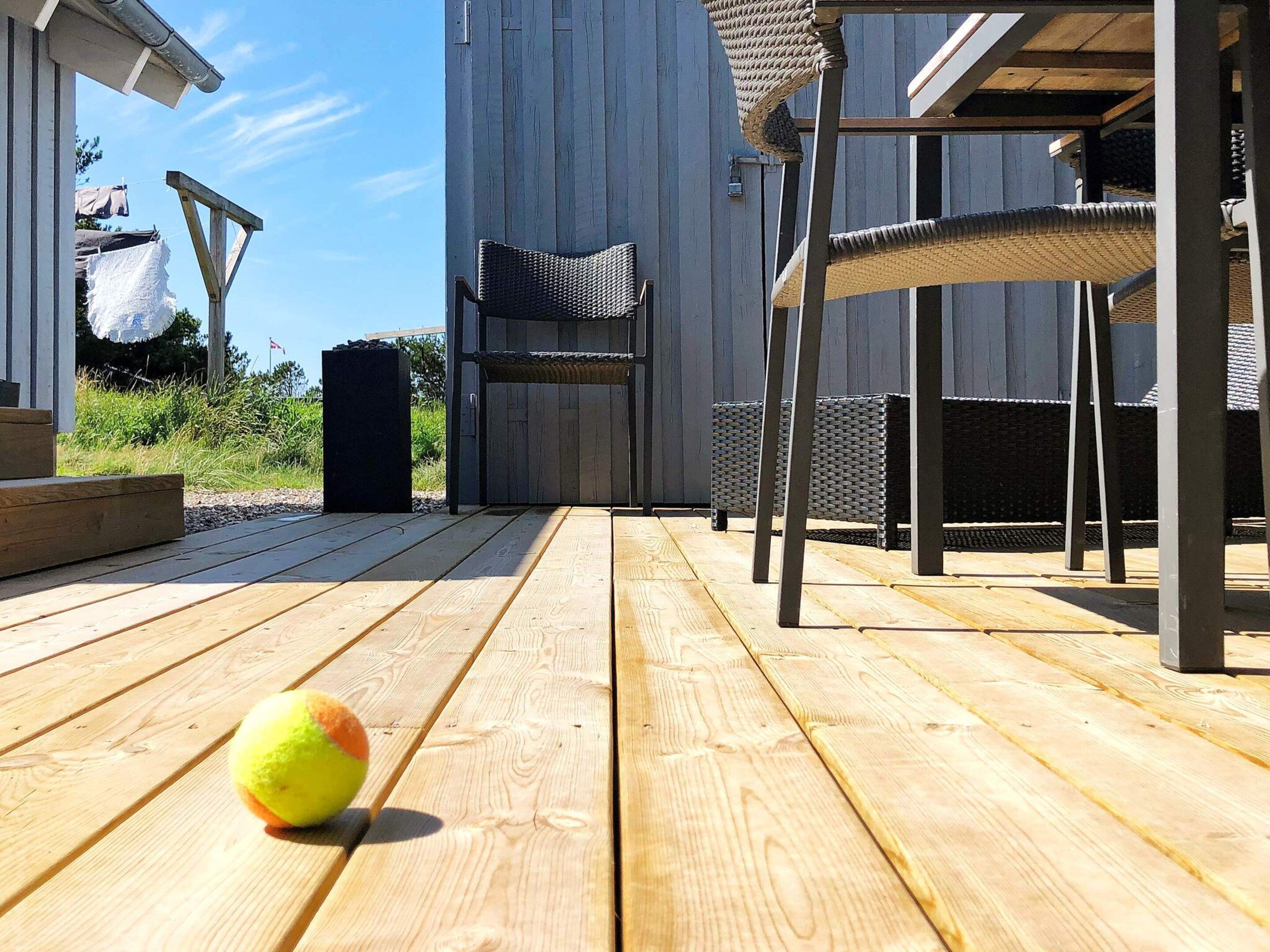 A wooden deck with outdoor furniture, including chairs and a table.