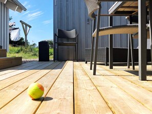 A wooden deck with outdoor furniture, including chairs and a table.