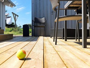 A wooden deck with outdoor furniture, including a chair and a table.