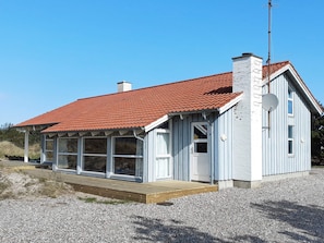 A single-story building with a red-tiled roof, a chimney, and a satellite dish.