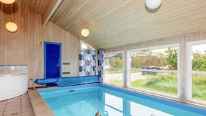 En swimmingpool med ett blått poolområde, ett bubbelbad och en dörr som leder till ett täckt område.