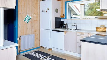Cocina compacta con un refrigerador blanco, cafetera y lavamanos.