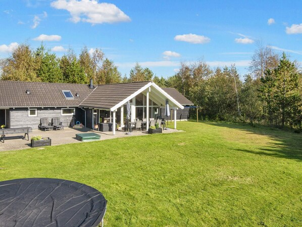 A house with a covered patio, outdoor seating, and a lawn.