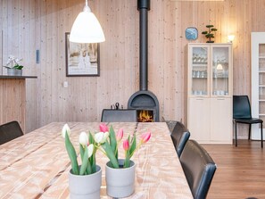 A dining area with a wooden table, chairs, a fireplace, and a cabinet with glass doors.