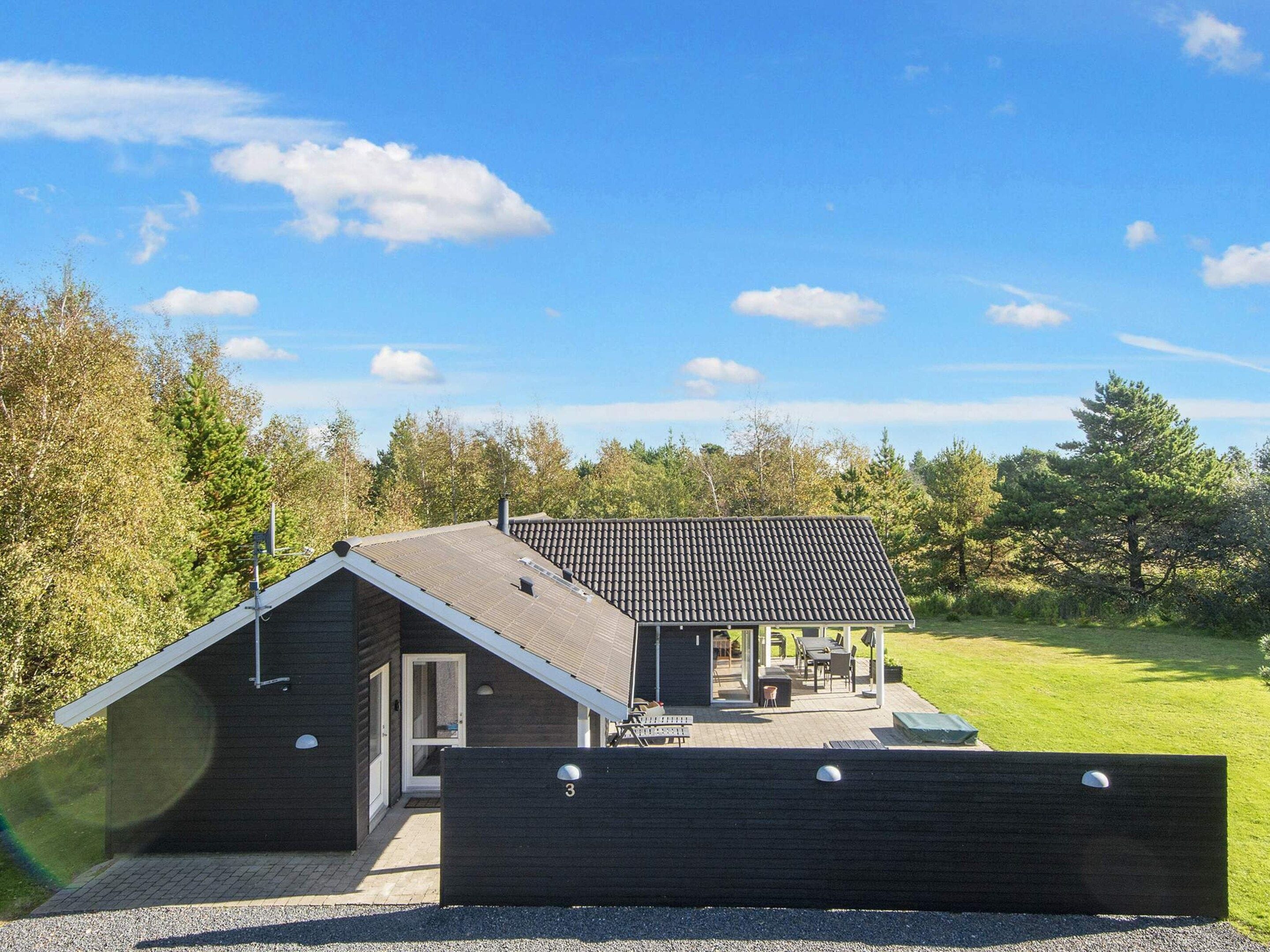 A modern house with a sloped roof, a covered patio, and a fenced yard.
