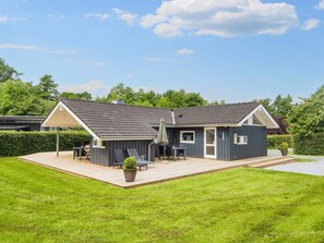 Une maison moderne à deux étages, dotée d’un patio couvert, d’un petit jardin et d’une pelouse bien entretenue.