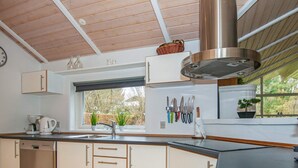 Una cocina moderna con ventana, techo de madera y campana extractora de acero inoxidable.