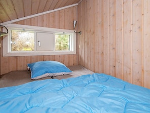 A room with a bed, a window, and a wooden ceiling.