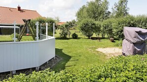 A residential backyard with a swimming pool, a covered outdoor seating area, and a garden with various plants and trees. - Holiday Home in Otterndorf (Otterndorf)