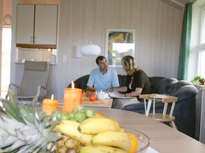A dining area with a table set for two, a candle, and a fruit bowl.